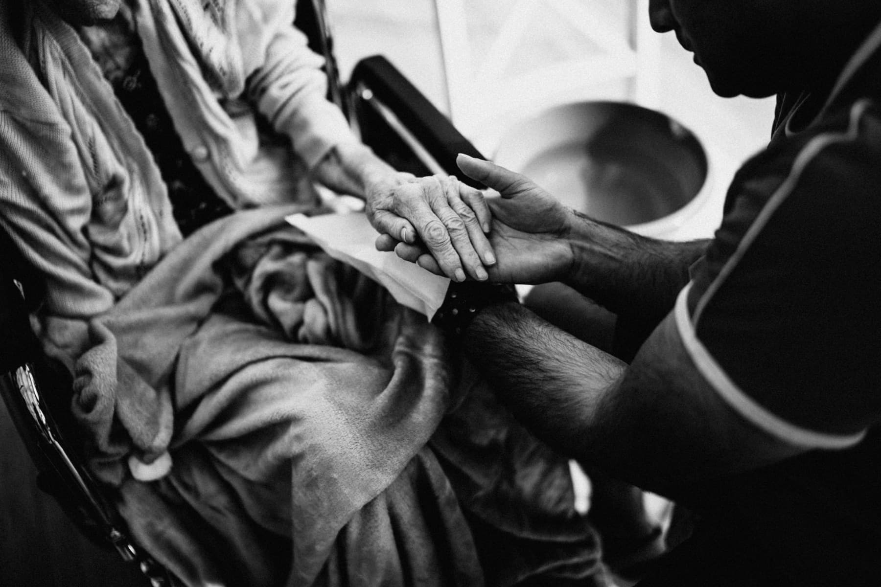 A caregiver gently holding an elderly person's hands